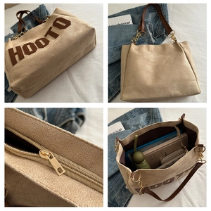 Detail view of beige tote bag showing HOOTO lettering, metal chain, and large interior space