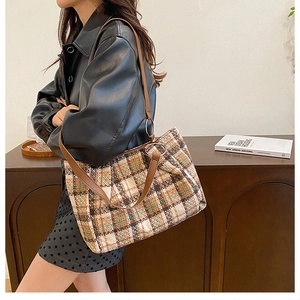 Detail of plaid tweed tote bag with brown leather strap and silver ring hardware