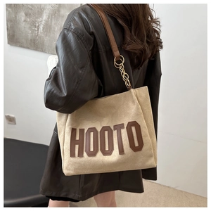 Detail of beige tote bag with HOOTO lettering and brown leather chain shoulder strap