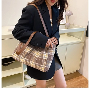 Brown plaid tote bag with leather strap shown on shoulder for sizing reference