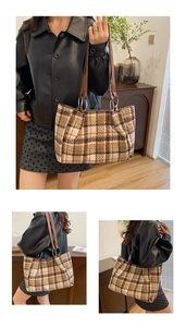Detail of classic plaid tote bag featuring brown leather straps and woven tweed texture