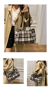 Detail of plaid tote bag with metal ring handles and black leather shoulder strap