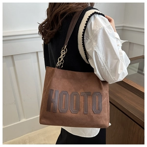 Detail of dark brown matte suede tote bag featuring metallic chain strap and HOOTO text