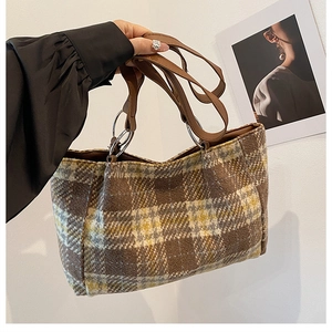 Detail of checkered plaid tote bag with brown leather handles and metal ring hardware