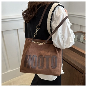 Brown suede tote bag with HOOTO letter patch and metal chain strap shown on model