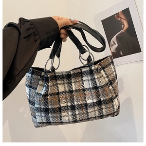 Detail of plaid wool tote bag with black leather handles and silver ring hardware