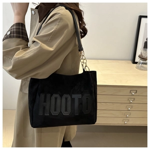 Detail of black suede tote bag with HOOTO embossed letters and chain shoulder strap