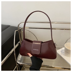 Detail of burgundy crescent shoulder bag showing glossy leather texture and logo