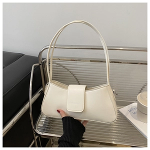 Detailed view of cream crescent shoulder bag with embossed logo on rippled metal shelf