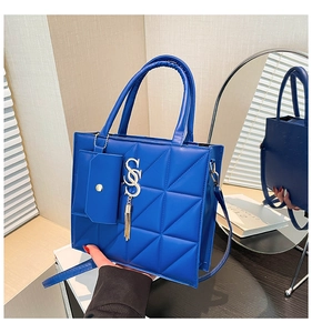 Detail of royal blue quilted handbag with gold S-logo, fringe tassel and mini chain pouch