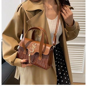 Brown crocodile texture handbag with gold letter clasp and tassel shown on model