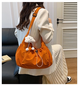 Detail view of bright orange nylon crossbody bag with drawstring design and cloud charm