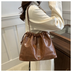 Brown soft leather shoulder bucket bag with stylish drawstring and bow detail for women.