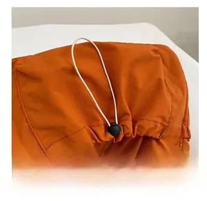 Detail of orange nylon crossbody bag showing water-resistant texture and white drawstring