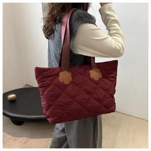 Detail of burgundy quilted tote bag with unique flower-shaped brown leather patches