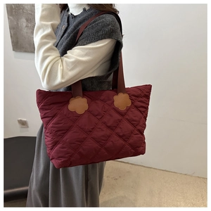 Quilted tote bag in burgundy featuring oversized puffer design and floral accents