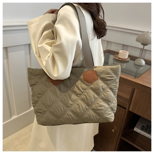 Detailed view of olive green quilted tote bag with floral leather accents on a nylon surface