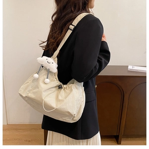 Beige nylon crossbody bag with adjustable strap and cute cloud charm worn by a model