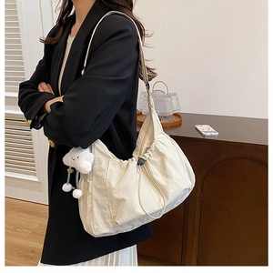 Detailed shot of spacious cream-colored dumpling bag featuring a cute white cloud charm