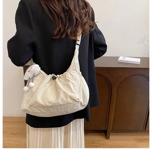 Detail of beige nylon crossbody bag with drawstring design and white cloud charm