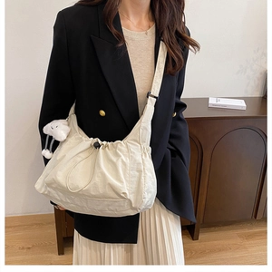 Minimalist beige nylon crossbody bag with drawstring design and cloud charm on model