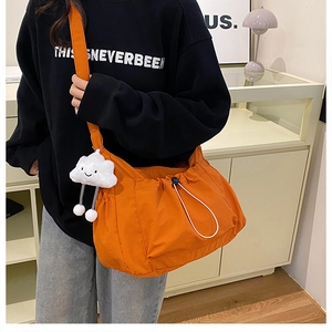 Close-up of orange canvas dumpling bag with drawstring closure and cloud charm detail