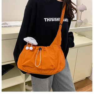 Lightweight bright orange nylon crossbody bag with drawstring and cloud charm accessory