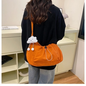 Stylish orange nylon crossbody bag with drawstring closure and cute plush charm on back
