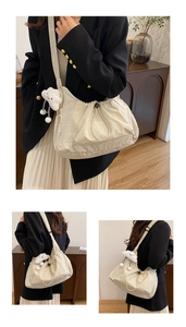 Detail view of beige canvas dumpling bag featuring pleated drawstring and cloud charm