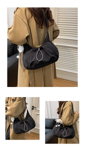 Detail view of black pleated nylon tote bag featuring white drawstring and plush cloud charm