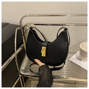 Close-up of black crescent moon bag with gold hardware on a modern display shelf