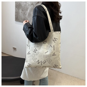 Detail of a large canvas tote bag with letter prints and branded shoulder straps
