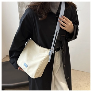 Sac bandoulière en toile beige chic avec sangle bleu clair et détail d'étiquette mode