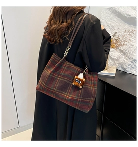 Detail of vintage plaid wool tote bag with brown leather straps and plush charm