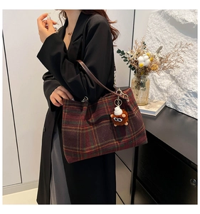 Detailed close-up of a vintage plaid tote bag with a brown plush animal pendant charm