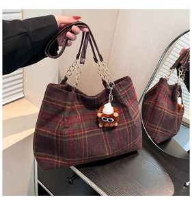 Detail of vintage plaid tote bag with gold chain strap and cute plush monster charm