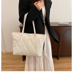 Détail du sac cabas beige matelassé montrant la broderie ondulée et la poignée en cuir