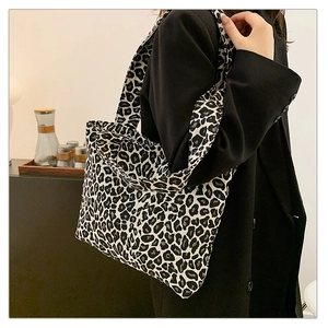 Leopard print canvas tote bag styled on black coat for a trendy minimalist fashion look