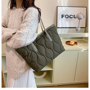 Vue latérale d'un grand sac cabas matelassé vert olive porté avec un manteau d'automne