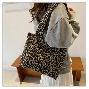 Detailed view of a large leopard print tote bag with wide shoulder strap on a model