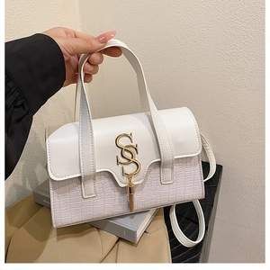 Detail of white patchwork handbag featuring gold SS hardware and elegant tassel accents