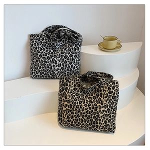 Detail view of large leopard print canvas tote bags in grey and brown on white stand