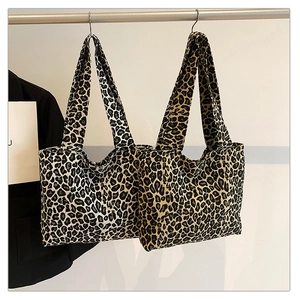 Detail view of canvas tote bags with leopard print in brown and grey hanging on a rack