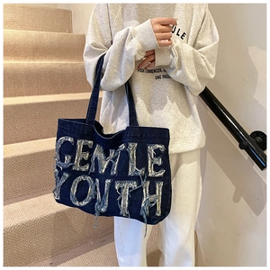 Détail du sac cabas en denim vintage avec design de lettres effilochées et style rétro