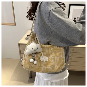 Detail of yellow plaid canvas tote bag with cute white cloud plush pendant and white strap