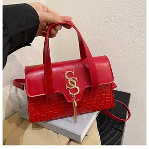 Close-up of red handbag featuring croc-embossed texture and golden SS metal logo