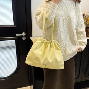 Large drawstring bucket bag in light yellow faux leather with a small silver bow detail