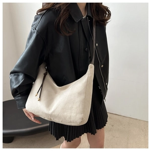 Detail of beige frosted leather hobo bag with side drawstring and metal buckle accents