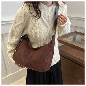 Detail of the white contrast stitching and matte suede texture on the dark brown tote bag