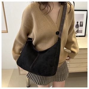Détail d'un grand sac hobo en daim noir avec surpiqûres blanches et bandoulière nouée